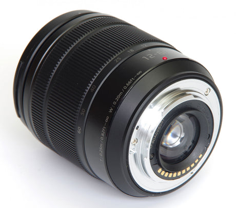 Angled close-up of black 12-60mm camera lens front glass and mounting ring