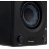 Close-up of black speaker woofer with blue ring and front panel volume and power buttons