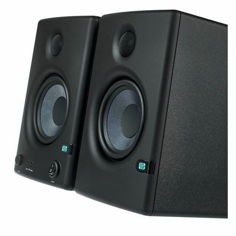 Close side view of black studio monitor speakers showing woofer cones and ports