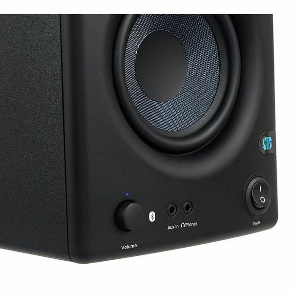 Close-up of studio monitor control panel: volume knob, headphone output, power button