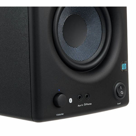 Close-up of studio monitor control panel: volume knob, headphone output, power button