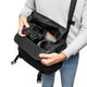 Black camera bag opened with inner compartments and camera lens inside