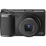 Black compact camera angled front view, prominent lens with visible lens markings
