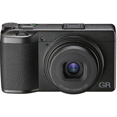 Black compact camera angled front view, prominent lens with visible lens markings