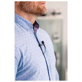 Lavalier microphone clipped to a blue button-up shirt collar, wired cable