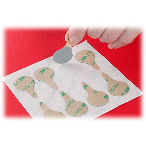 Adhesive lavalier microphone covers on backing sheet held by hand