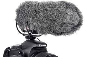 Gray foam microphone windscreen with shock mount straps on a camera top