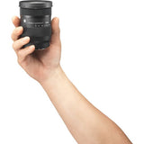 Black camera lens held in hand, showing front barrel and lens cap area