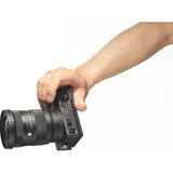 Hand holding black 16-28mm lens from the rear, showing buttons and mount