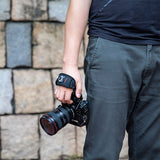 Black camera hand strap worn on wrist while holding a mirrorless camera