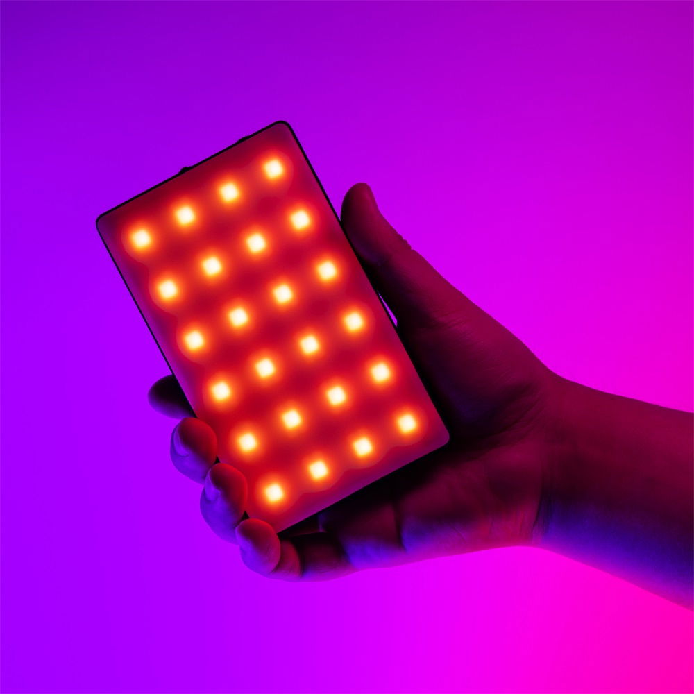 LED video light in hand, illuminated orange LED matrix on dark housing