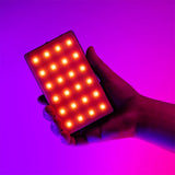 LED video light in hand, illuminated orange LED matrix on dark housing