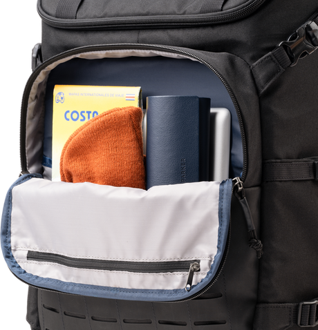 Open black backpack showing interior organizer sleeve with books and a passport-sized item