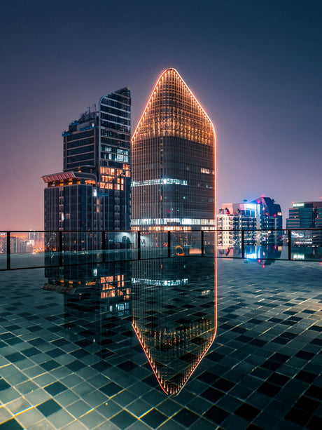 Tall reflective glass prism sculpture showing a city skyline at dusk