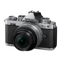 Silver mirrorless camera with black textured grip and attached zoom lens