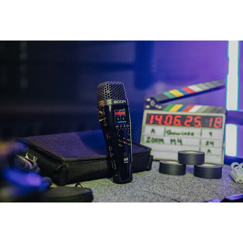 Stereo mic recorder with top grille and lit screen, set beside compact accessory case